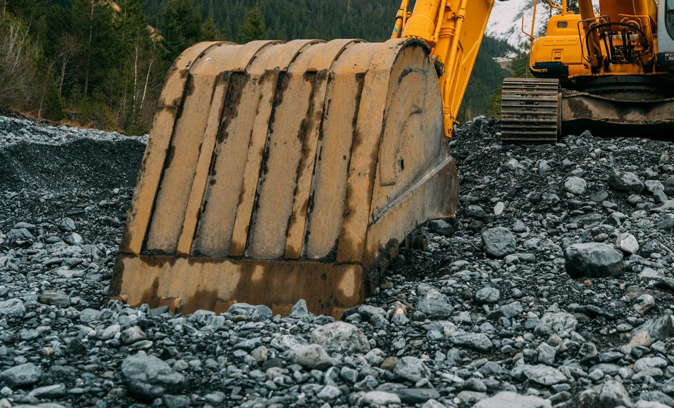Worn excavator bucket on a gravel site